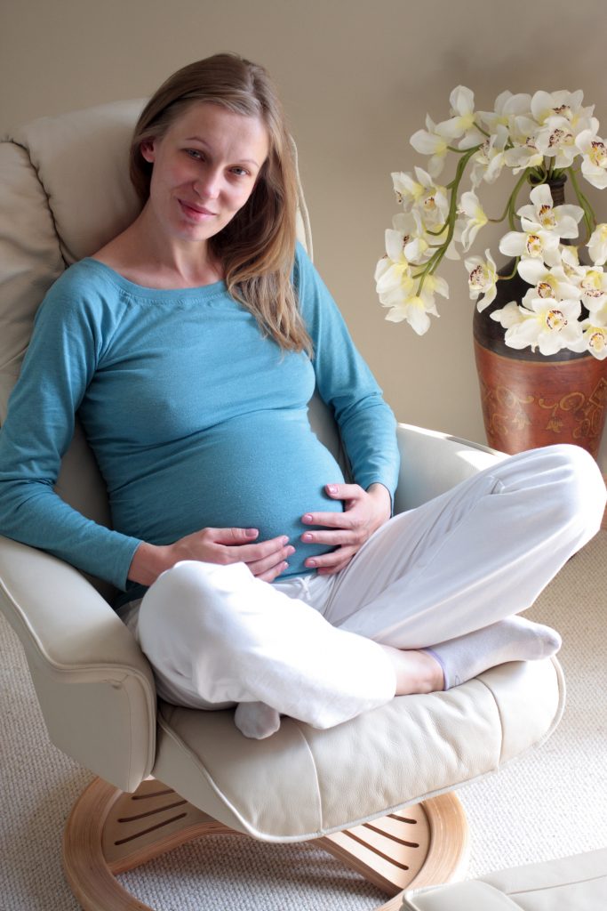Photo of smiling pregnant women sitting on chair